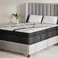 A luxury mattress on a matching upholstered bed frame with a tall gray tufted headboard, styled in a modern bedroom setting.