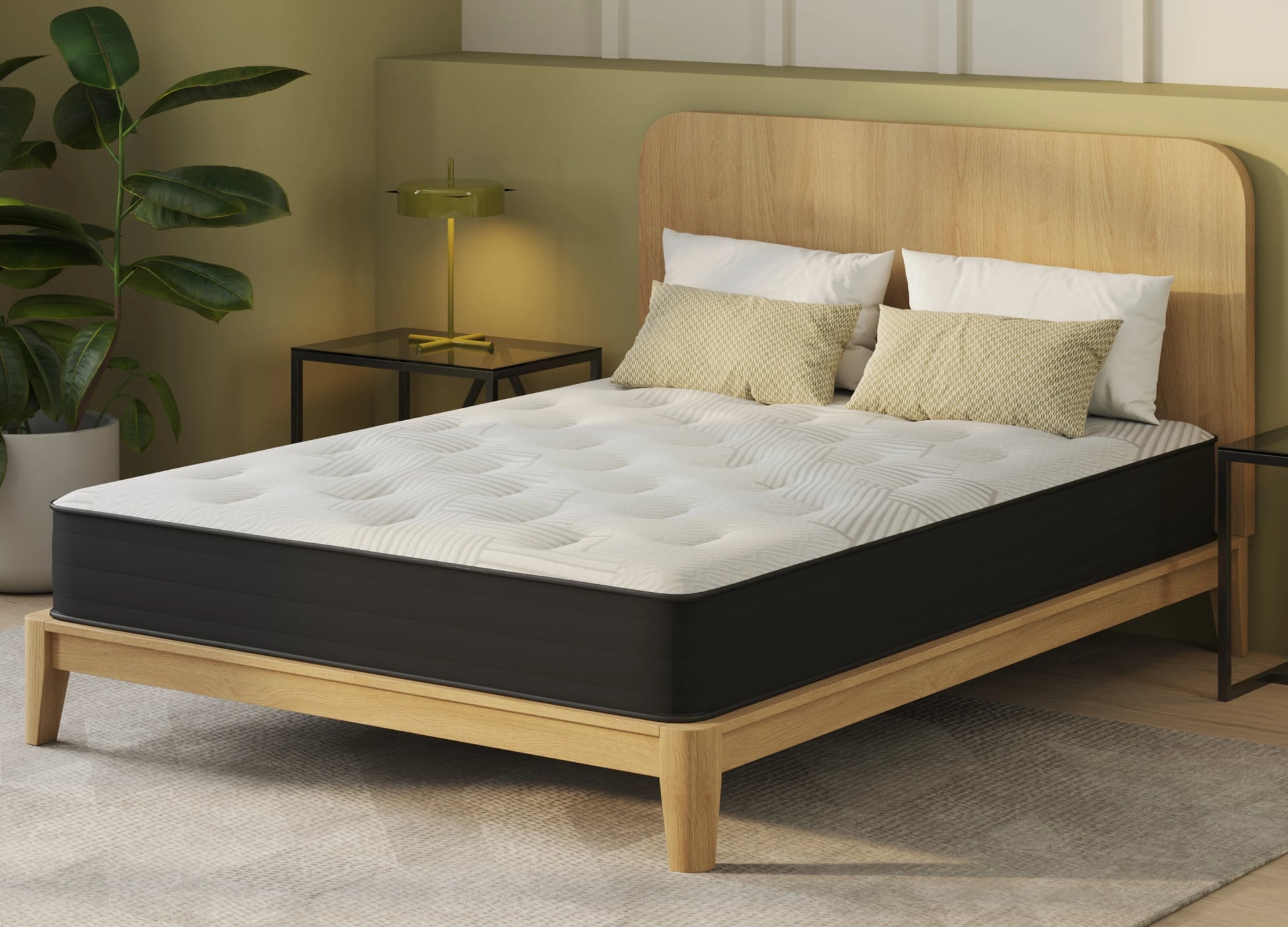 A mattress on a light wood bed frame with a tall matching headboard, styled in a bedroom setting with pillows, a side table, lamp, and plant.